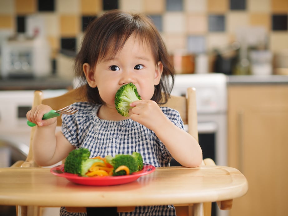 baby girl eating  vegetable at home